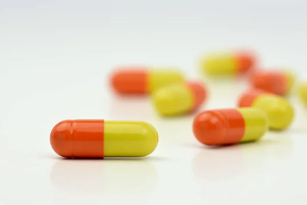 Foto de cerca de píldoras de color amarillo anaranjado aisladas sobre fondo blanco con fondo borroso —  Fotos de Stock