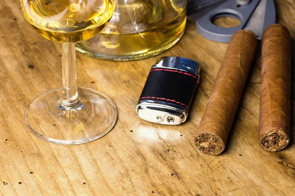 Sigaro con bottiglia e bicchiere di whisky, accendino e tagliasigari su una vecchia tavola di legno — Foto Stock