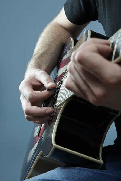 Mãos de um jovem tocando guitarra com uma bandeira americana — Fotografia de Stock