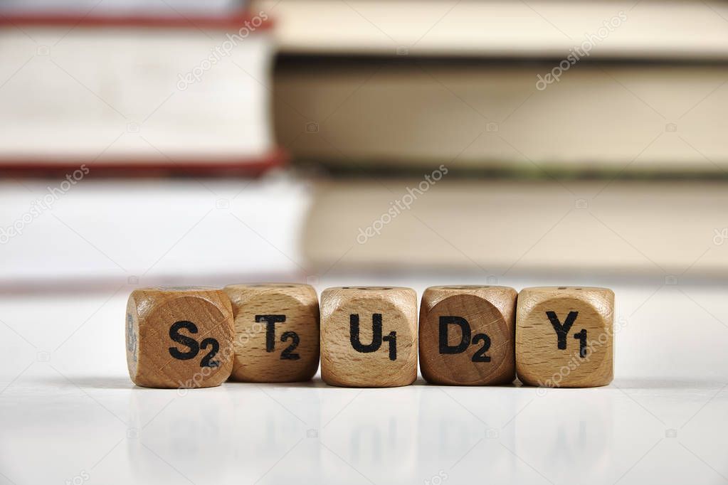 Wooden dice with the words Study, and books in the background