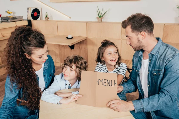 Familia con la lista de menú en la cafetería — Foto de Stock