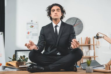 businessman meditating at workplace clipart