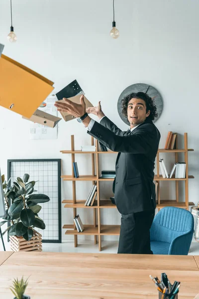 Businessman throwing folders in office — Free Stock Photo