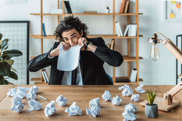 businessman biting paper at workplace