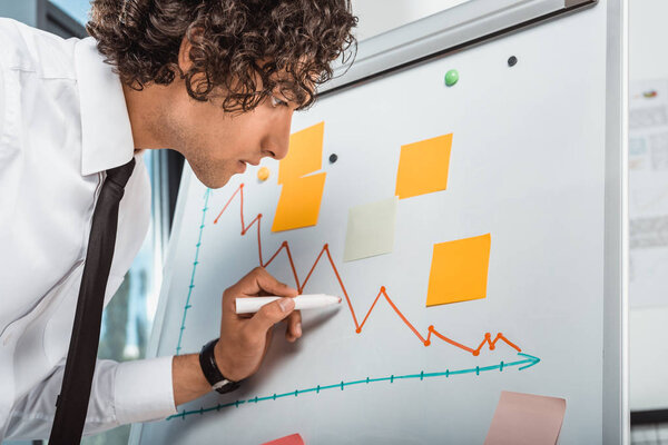 бизнесмен рисует графику на белой доске
