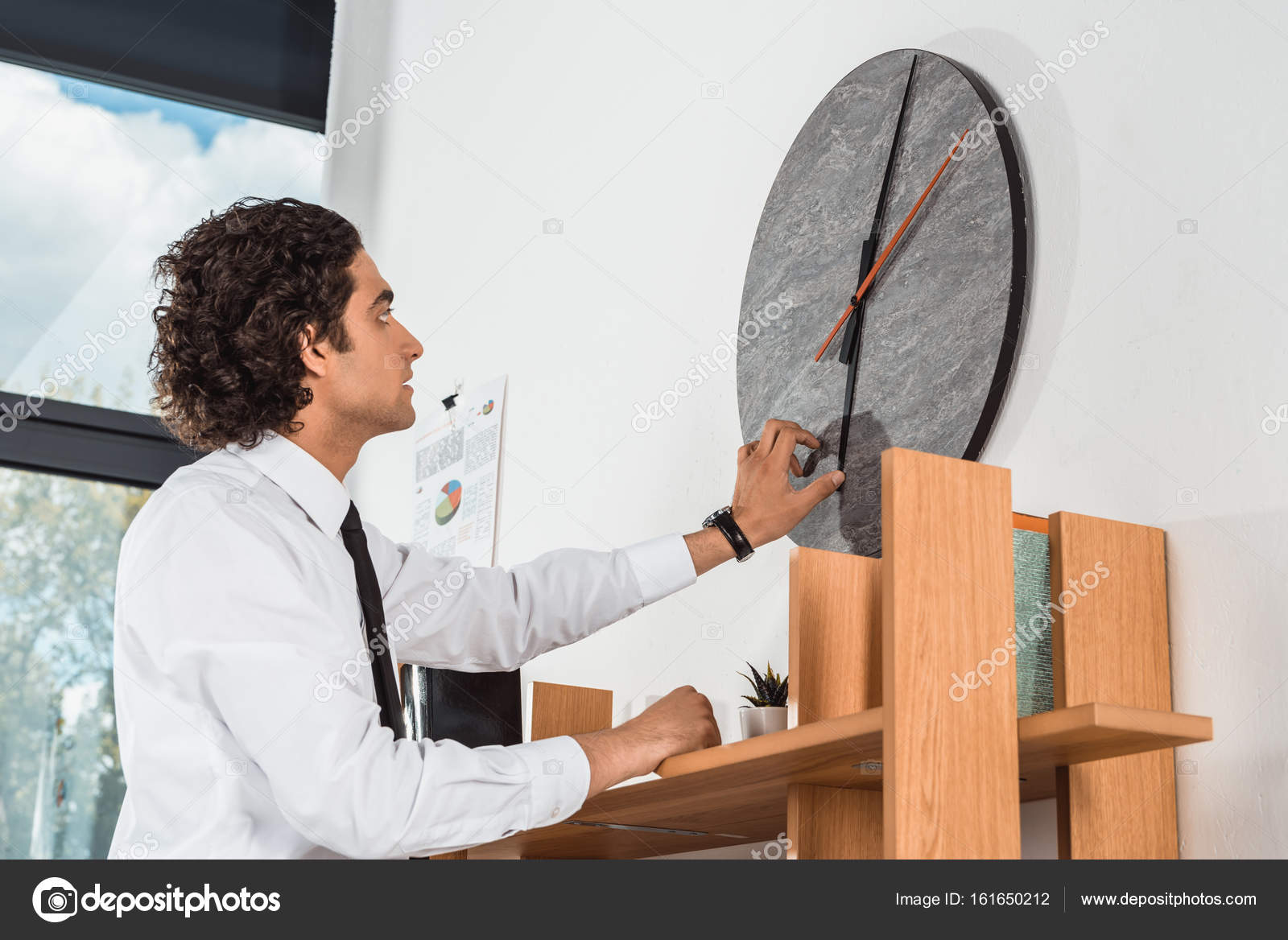 Businessman setting time on clock in office — Stock Photo © AlexNazaruk