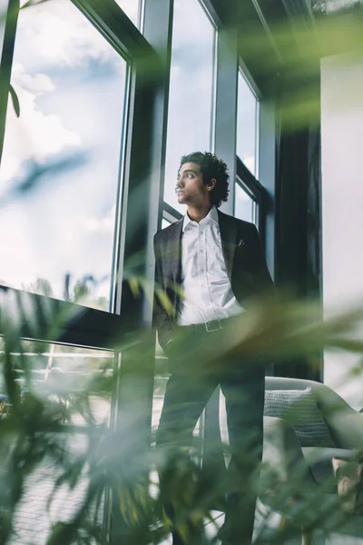 Бизнесмен, стоящий у окна в офисе — стоковое фото