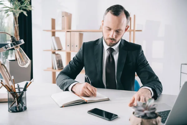 Handsome businessman writing in notebook — Stock Photo, Image