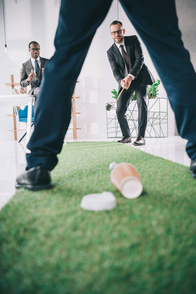 бизнесмены играют в мини-гольф
