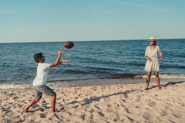 mother and son playing with ball on beach clipart