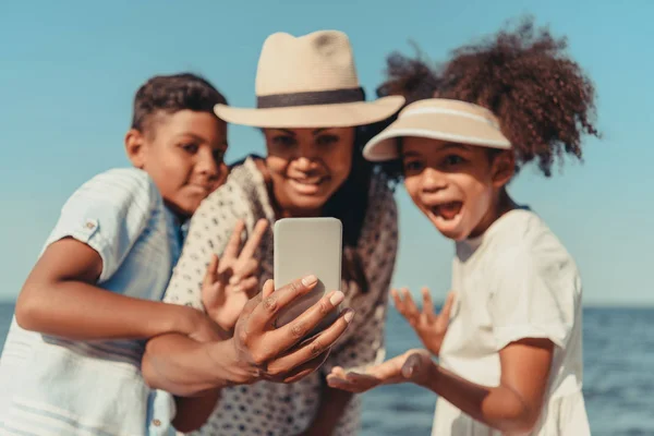 Äiti lasten kanssa ottaen selfie rannalla — kuvapankkivalokuva