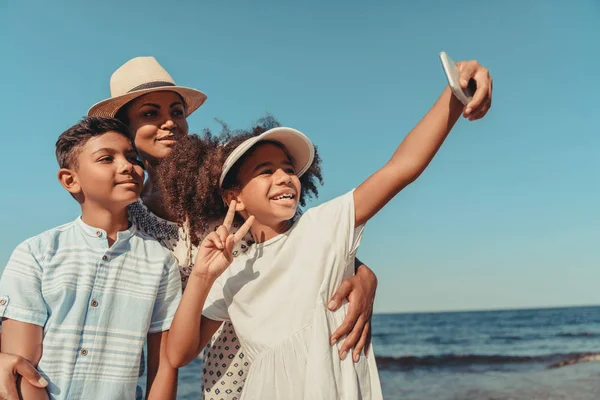 Mãe com filhos tirando selfie na praia — Fotografia de Stock