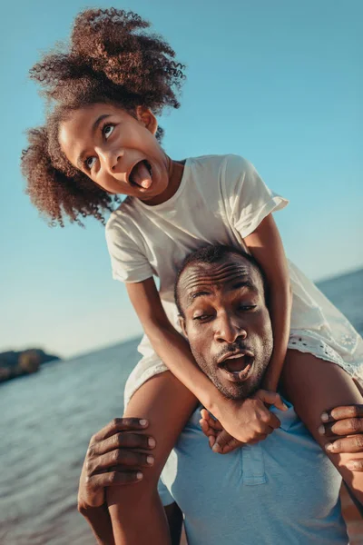 African american father carrying daughter on beach — Stock Photo, Image