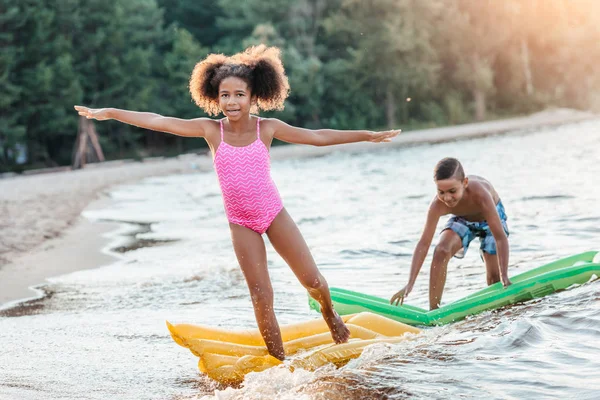 Hermanos con colchones de natación en la playa — Foto de Stock