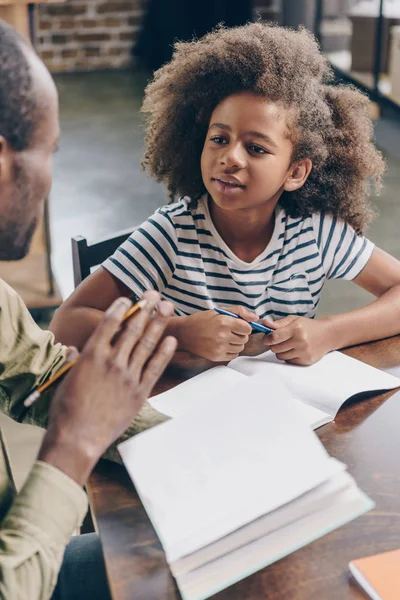 Little girl listening to father with textbook — Stock Photo, Image