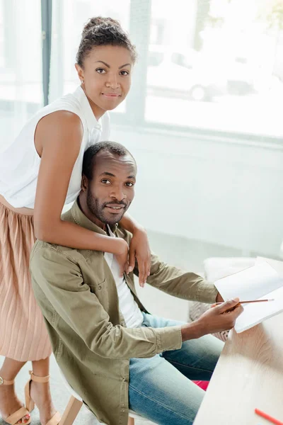 Wife hugging man holding notebook — Free Stock Photo