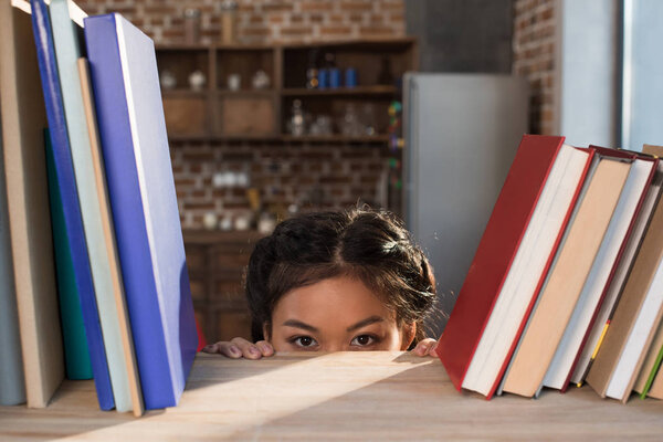 студент прячется за книжной полкой
 