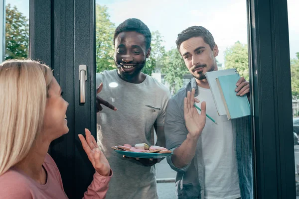 Frau winkt Freunden hinter Fenster zu — Stockfoto