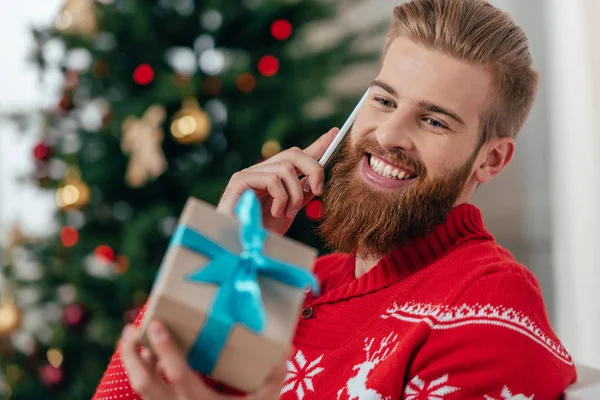 Мужчина разговаривает по телефону и смотрит на подарок — стоковое фото