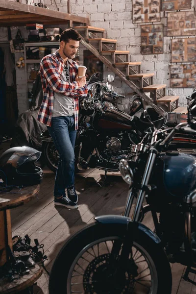 Mann in Werkstatt mit Oldtimer-Motorrädern — Stockfoto