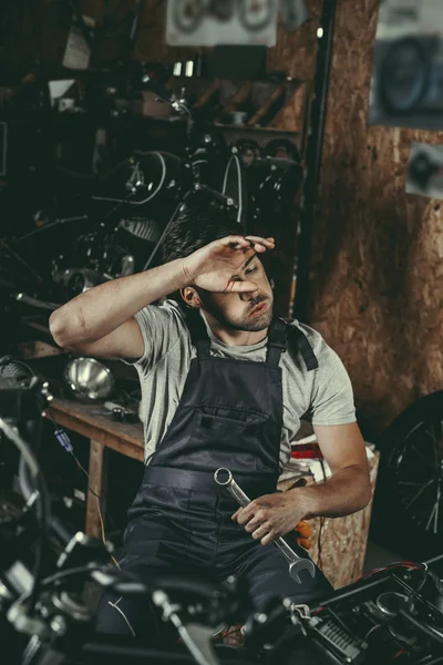 Tired mechanic repairing motorbike — Stock Photo, Image