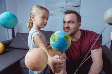 Girl showing father model of Earth   clipart