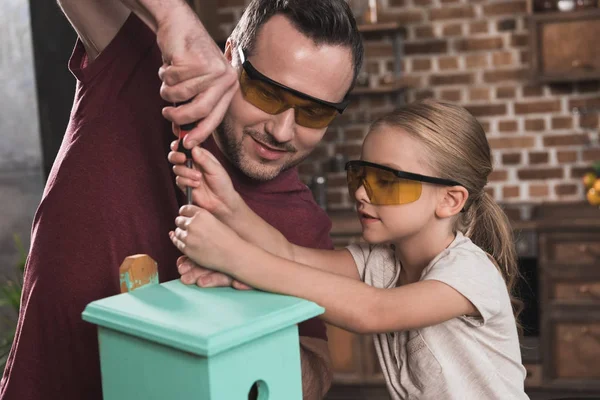 Tochter hilft Vater beim Vogelhäuschen bauen — Stockfoto