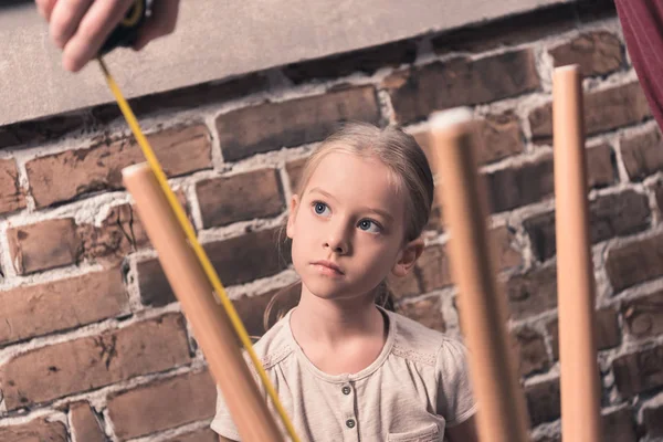 Daughter looking how father measuring table — Stock Photo, Image