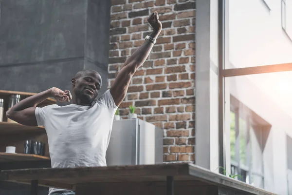 Africano americano hombre estiramiento en cocina - foto de stock