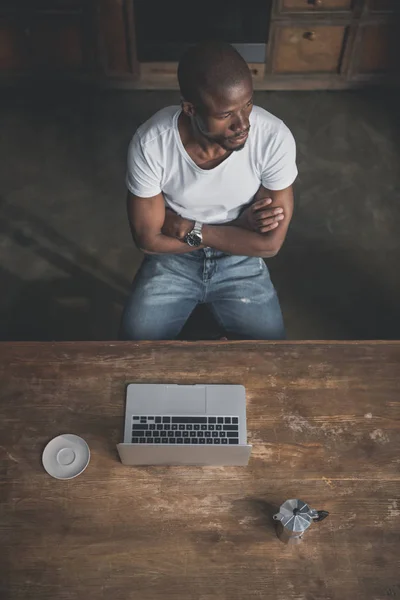 Hombre afroamericano con portátil en la mesa - foto de stock