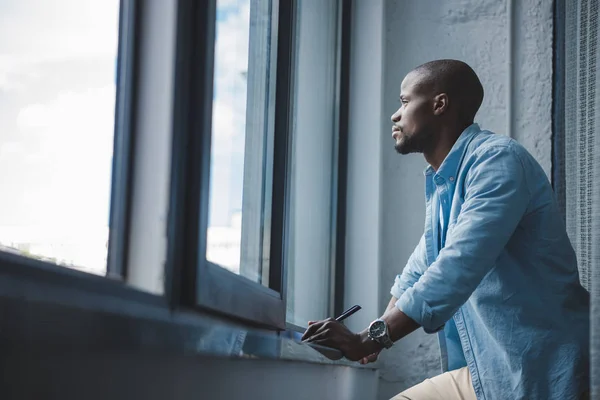 Afro-américain homme regardant la fenêtre — Photo de stock