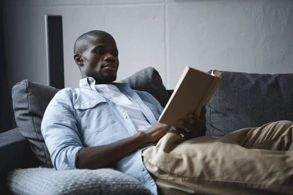 Hombre afroamericano leyendo libro - foto de stock