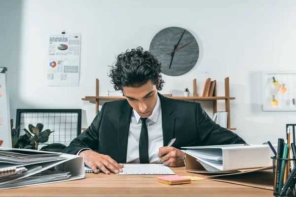 Empresario que trabaja con papeles en el lugar de trabajo - foto de stock