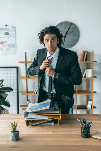 Businessman tying necktie at workplace — Stock Photo