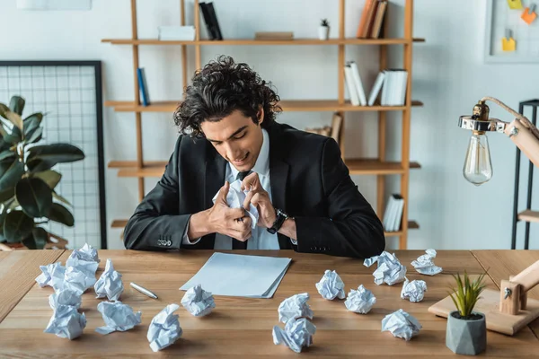 Сердитий бізнесмен стискає папери на робочому місці — стокове фото