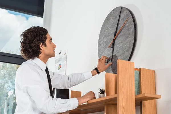 Homme d'affaires réglage de l'heure sur horloge dans le bureau — Photo de stock