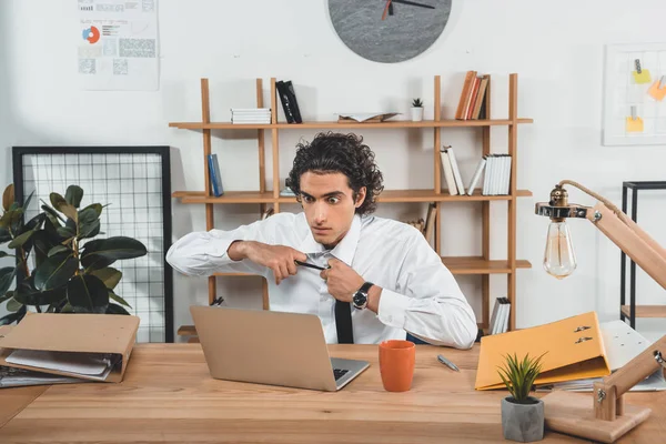 Hombre de negocios sentado en el lugar de trabajo con portátil - foto de stock