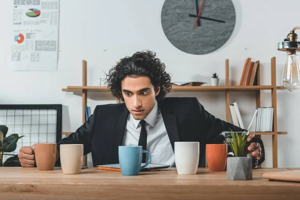 Businessman with tablet and coffee cups at workplace — Stock Photo