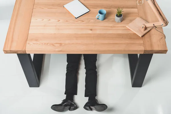Бизнесмен, лежащий под столом — стоковое фото