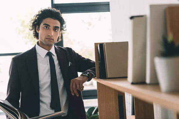 Geschäftsmann steht im Büro am Bücherregal — Stockfoto