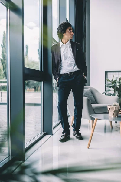 Hombre de negocios de pie en la ventana en la oficina - foto de stock