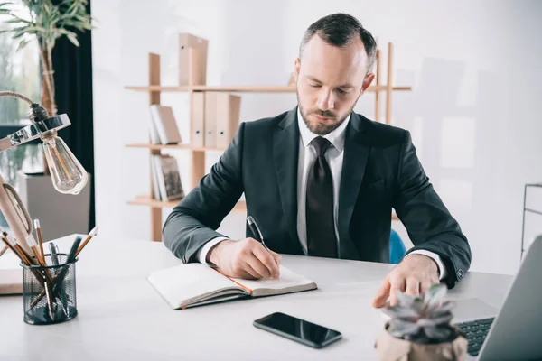 Bonito homem de negócios escrevendo em notebook — Fotografia de Stock