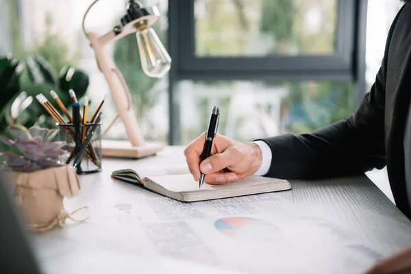 Hombre de negocios escribiendo en cuaderno - foto de stock