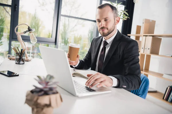 Businessman using laptop with coffee — Stock Photo