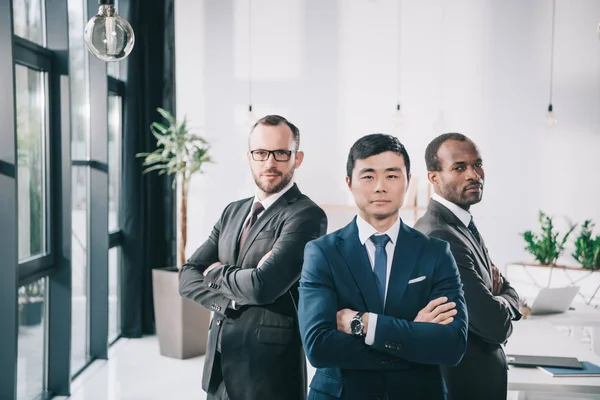 Hombres de negocios multiéticos con brazos cruzados - foto de stock