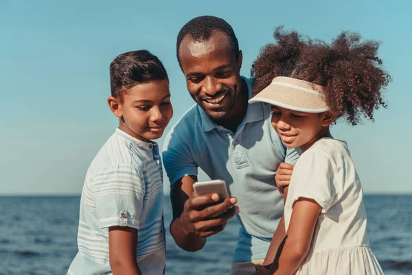 Pai e filhos usando smartphone — Fotografia de Stock