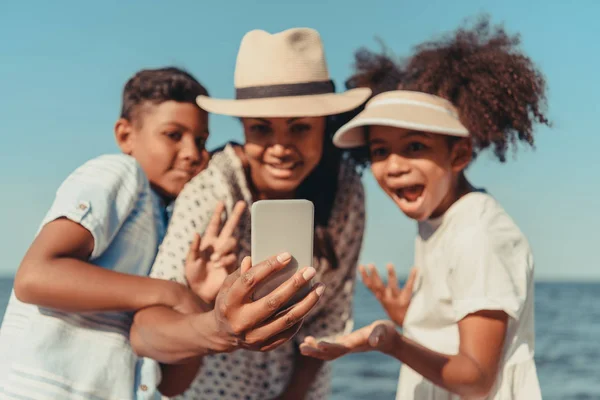 Madre con niños tomando selfie en la playa - foto de stock