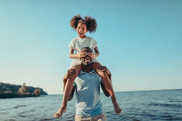 Père afro-américain portant fille sur la plage — Photo de stock