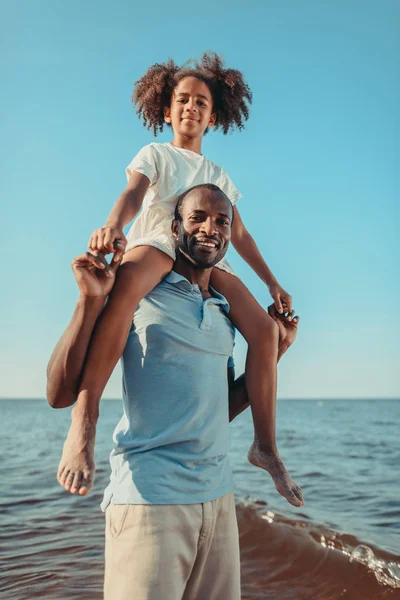 Père afro-américain portant fille sur la plage — Photo de stock