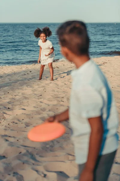 Irmãos brincando com disco voador na praia — Fotografia de Stock